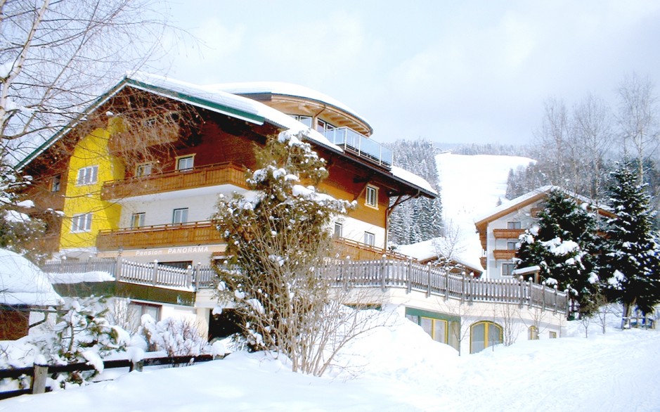 Die Pension Panorama im Winter - im Hintergrund die Piste